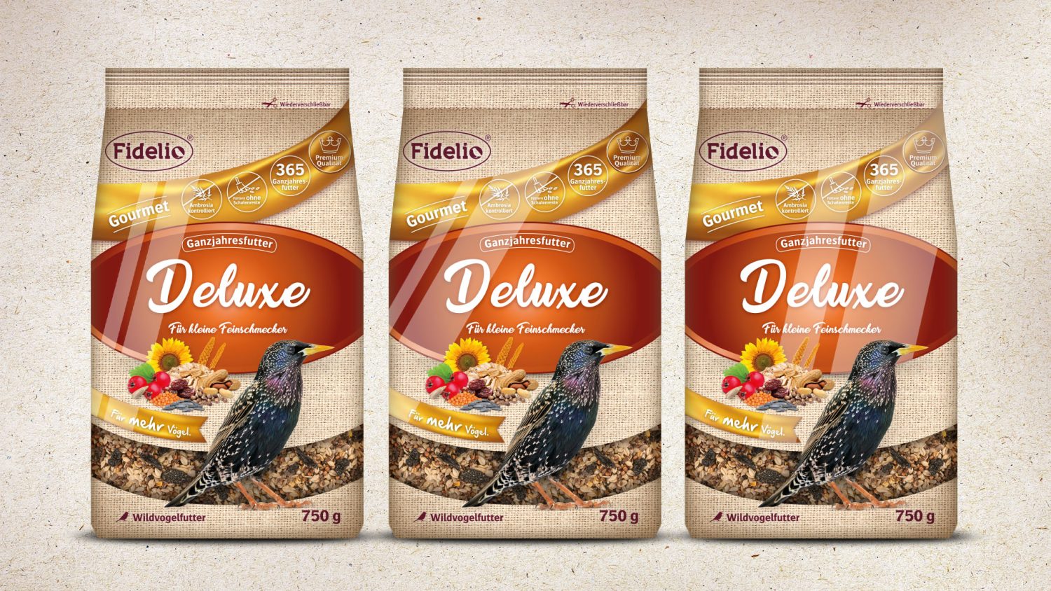 Drei Packungen des Fidelio Wildvogelfutters „Deluxe“ der Linie „Gourmet“. Reflexe auf der Front weisen auf die partielle Glanzlackierung hin.